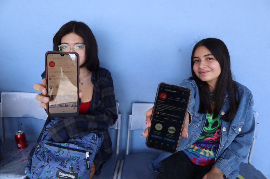 Two young students show their smartphones featuring radio ensena podcast in Chile.